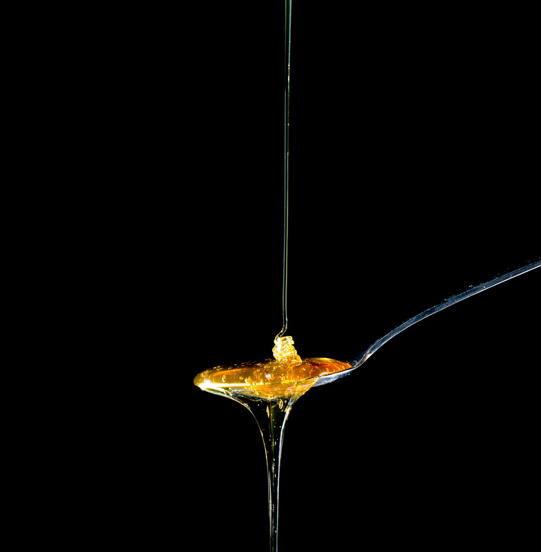 Honey in a Spoon on Black Background